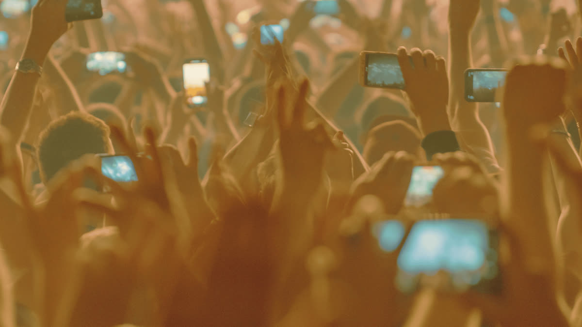 Festivalpublikum mit erhobenen Händen und Handys, die das Konzert filmen
