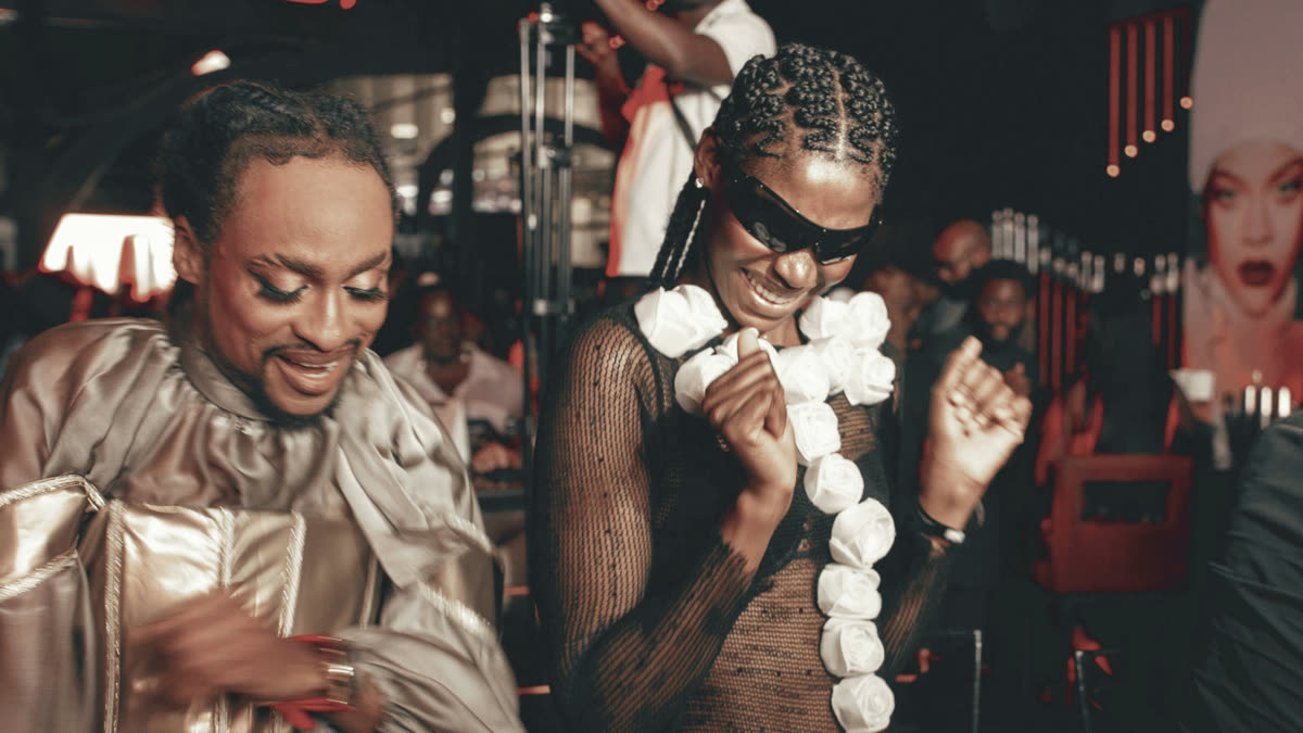 Two smiling, stylishly dressed clubbers dancing at a party under red lights